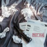 Scene of financial distress with bankruptcy notice, past due bills, and crumpled papers on a bed.